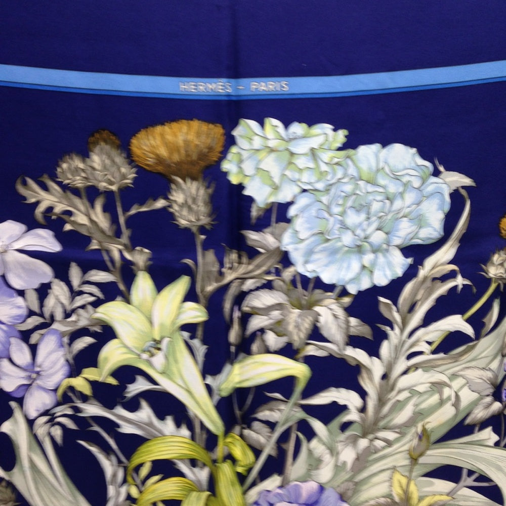 Hermes Regina Floral Scarf over a Blue Backgound